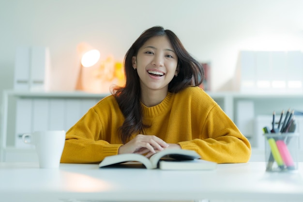 Photo une jeune femme qui lit un livre dans la bibliothèque elle sourit et a l'air heureuse