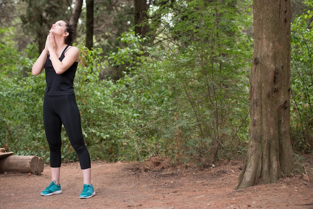 Jeune femme qui s'étend avant de courir dans la forêt boisée de formation et d'exercice pour Trail Run Marathon Endurance Fitness Mode de vie sain Concept