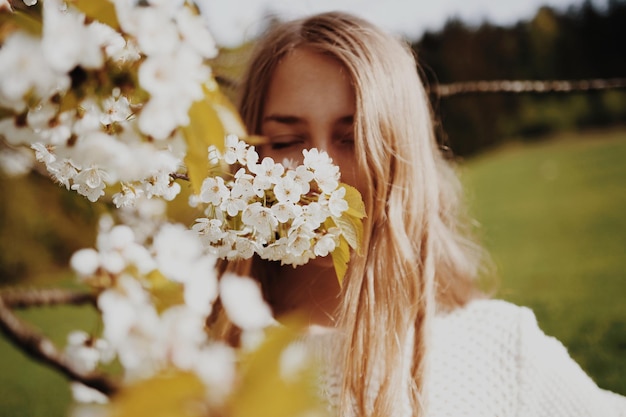 Une jeune femme qui sent les fleurs dans le parc.