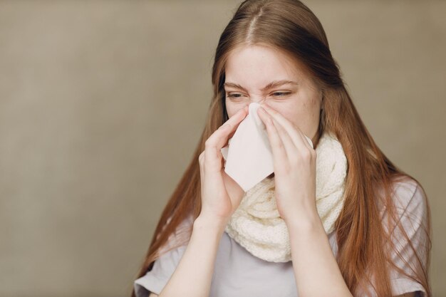 Une jeune femme qui souffle le nez a la grippe, la catarrhée, la maladie, le traitement du rhume.