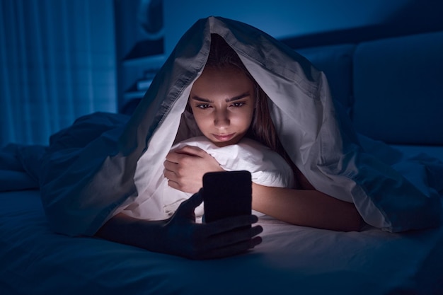 Une jeune femme qui utilise son téléphone portable la nuit.