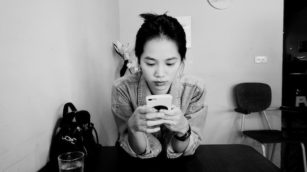 Photo une jeune femme qui utilise un téléphone portable sur la table.