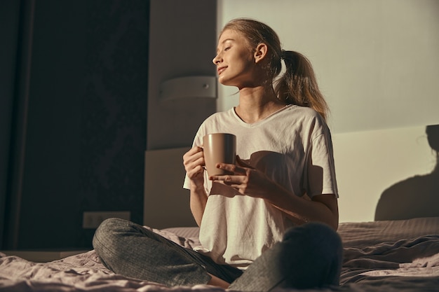 Jeune femme de race blanche au lit le matin de détente