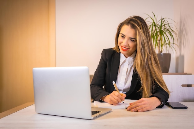 Jeune femme de race blanche blonde avec un café travaillant avec l'ordinateur