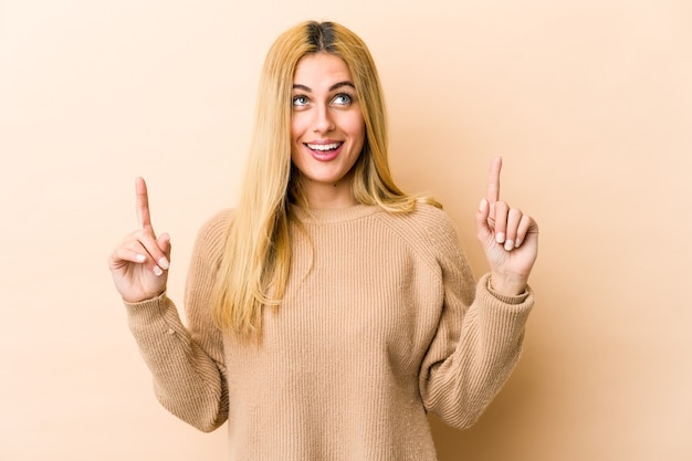 Jeune femme de race blanche blonde indique avec les deux doigts avant montrant un espace vide.