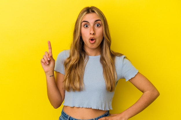 Jeune femme de race blanche blonde isolée sur un mur jaune ayant une idée