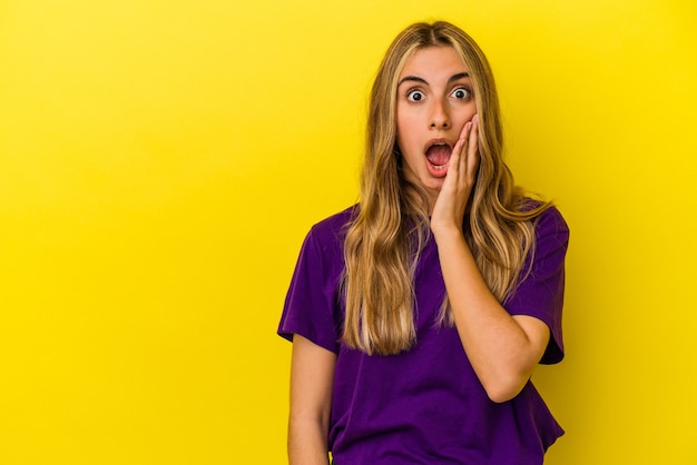 Jeune femme de race blanche blonde isolée sur le mur jaune crie fort, garde les yeux ouverts et les mains tendues