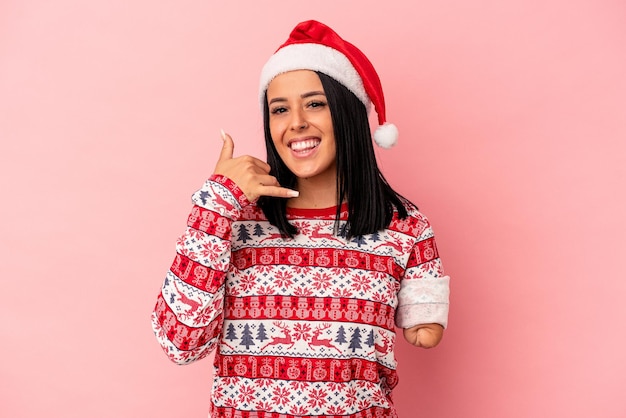 Jeune femme de race blanche avec un bras célébrant Noël isolé sur fond rose montrant un geste d'appel de téléphone portable avec les doigts.