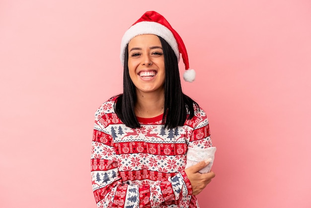 Jeune femme de race blanche avec un bras célébrant Noël isolé sur fond rose en riant et en s'amusant.