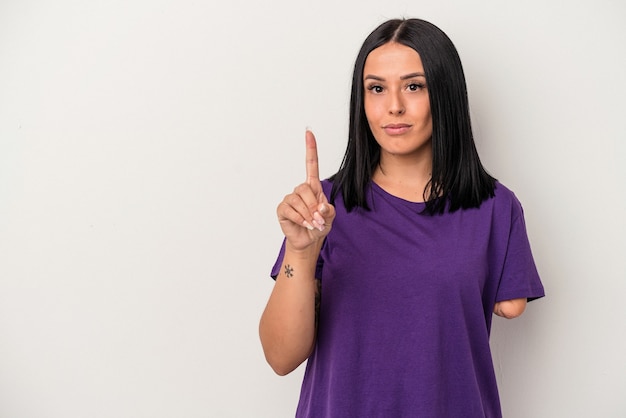 Jeune femme de race blanche avec un bras isolé sur fond blanc montrant le numéro un avec le doigt.