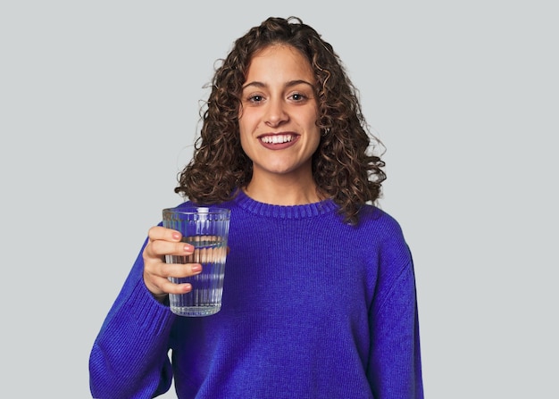 Une jeune femme de race blanche avec une carrure athlétique et des vêtements de sport tenant un verre d'eau