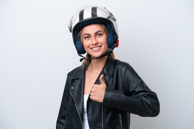 Jeune femme de race blanche avec un casque de moto isolé sur fond blanc donnant un coup de pouce geste