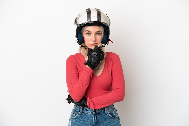 Jeune femme de race blanche avec un casque de moto isolé sur fond blanc pensant