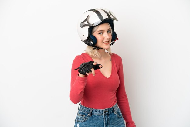 Jeune femme de race blanche avec un casque de moto isolé sur fond blanc pointant vers l'avant avec une expression heureuse