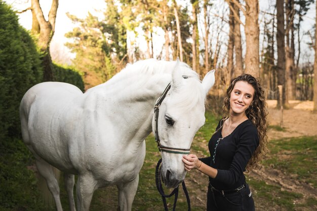 Jeune femme de race blanche avec un cheval dans un centre équestre