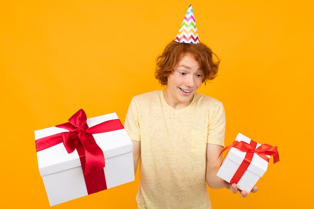 Jeune femme de race blanche est titulaire d'une boîte blanche avec des cadeaux et des cris de bonheur isolé sur orange