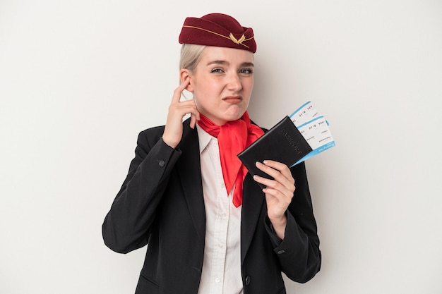 Jeune Femme De Race Blanche Hôtesse De L'air Tenant Un Passeport Isolé Sur Fond Blanc Couvrant Les Oreilles Avec Les Mains.