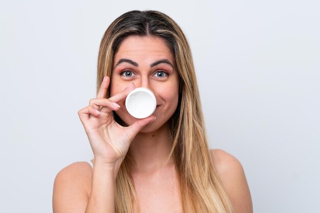 Jeune femme de race blanche isolée sur fond blanc avec une crème hydratante