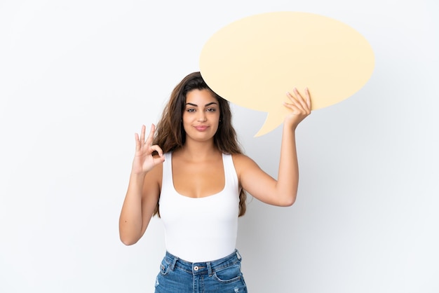 Jeune femme de race blanche isolée sur fond blanc tenant une bulle vide et faisant signe OK