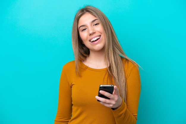 Jeune femme de race blanche isolée sur fond bleu à l'aide de téléphone mobile