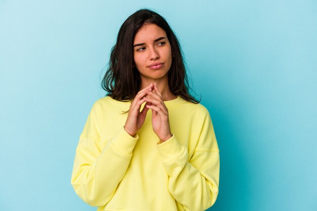 Jeune femme de race blanche isolée sur fond bleu, élaboration d'un plan à l'esprit, mise en place d'une idée.