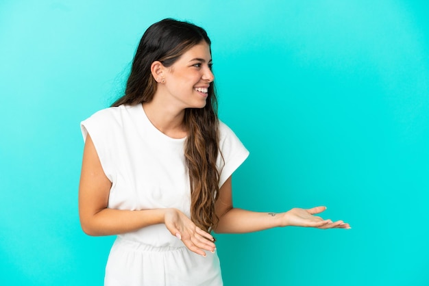 Jeune femme de race blanche isolée sur fond bleu avec une expression de surprise tout en regardant de côté