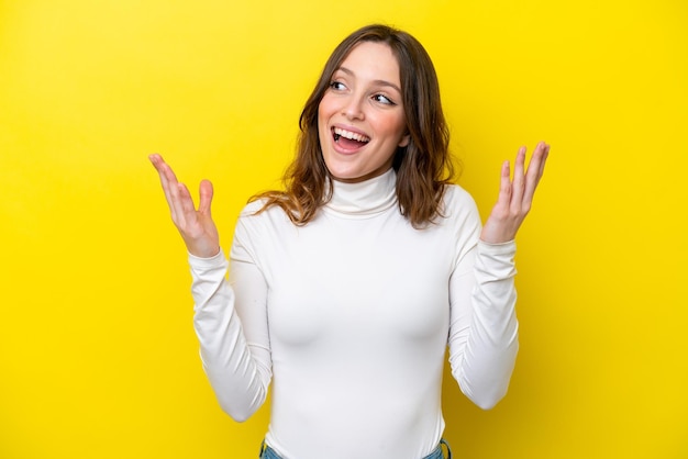 Jeune femme de race blanche isolée sur fond jaune avec une expression faciale surprise