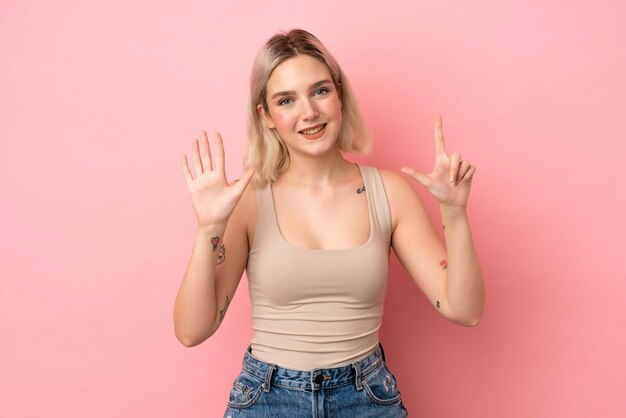 Jeune femme de race blanche isolée sur fond rose comptant sept avec les doigts