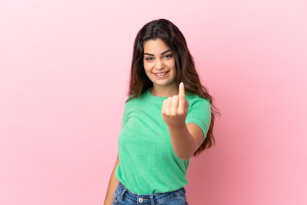 Jeune femme de race blanche isolée sur fond rose faisant un geste à venir