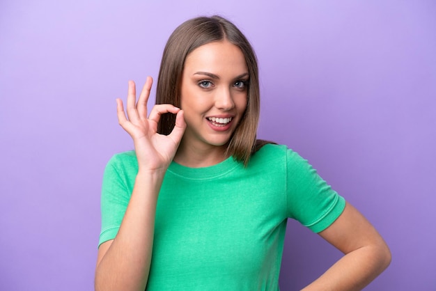 Jeune femme de race blanche isolée sur fond violet montrant un signe ok avec les doigts