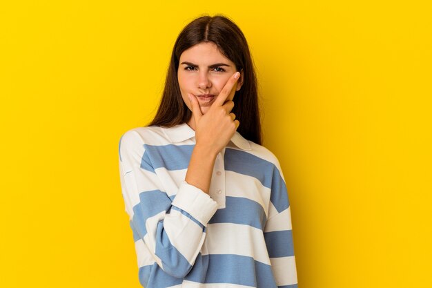 Jeune femme de race blanche isolée sur un mur jaune en contemplant, en planifiant une stratégie, en réfléchissant à la manière d'une entreprise