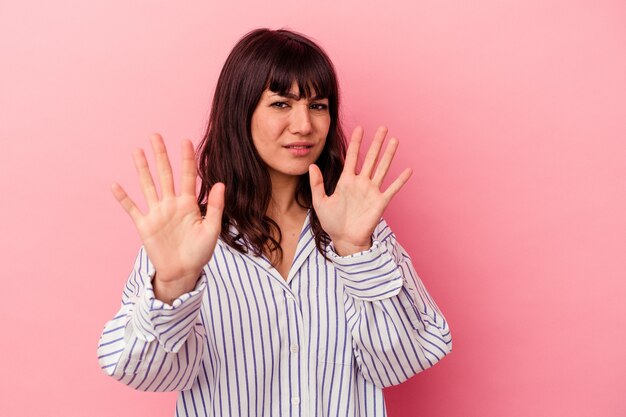 Jeune femme de race blanche isolée sur un mur rose rejetant quelqu'un montrant un geste de dégoût.