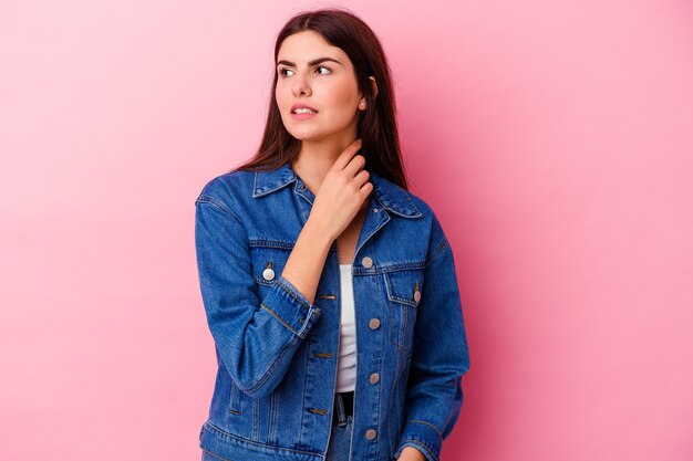 Jeune femme de race blanche isolée sur un mur rose souffre de douleurs dans la gorge en raison d'un virus ou d'une infection.