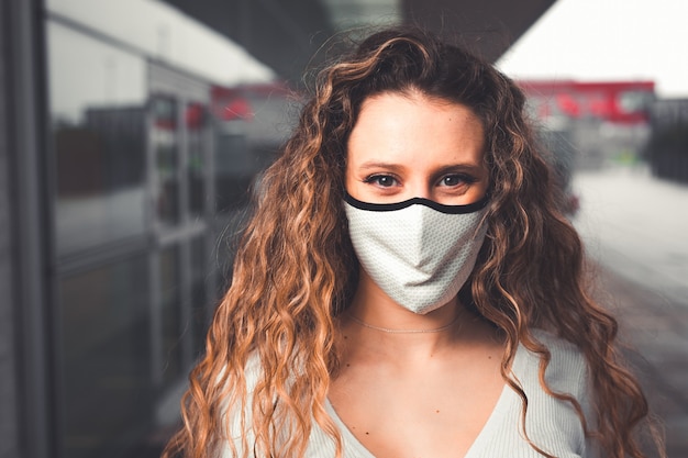 Jeune femme de race blanche avec un masque dans une zone urbaine