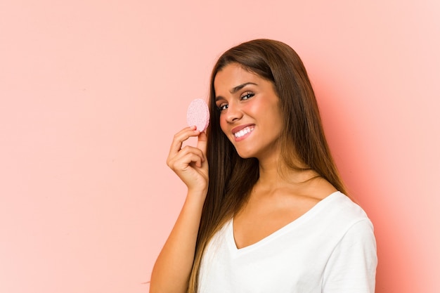 Jeune femme de race blanche nettoyant son visage avec un disque facial isolé