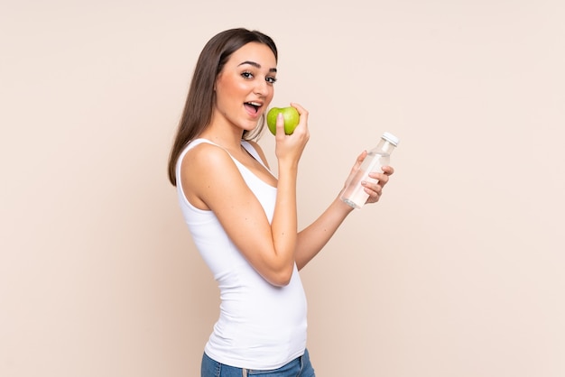 Jeune femme de race blanche avec une pomme et avec une bouteille d'eau