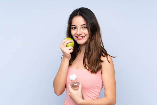 Jeune femme de race blanche avec une pomme et avec une bouteille d'eau