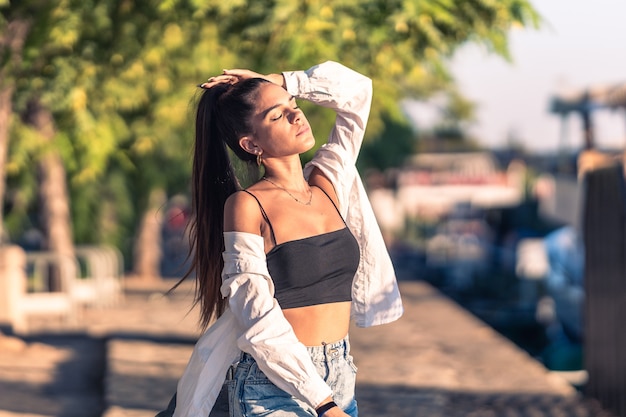 Jeune femme de race blanche posant tout en prenant un bain de soleil dans la rue