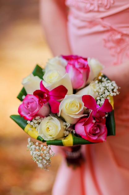 Jeune femme de race blanche en robe de dentelle rose est titulaire d'un bouquet de fleurs et de roses de jardin roses dans son h