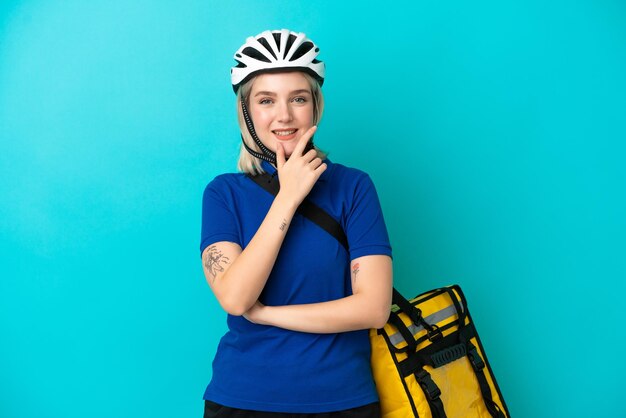 Jeune femme de race blanche avec sac à dos thermique isolé sur fond bleu souriant