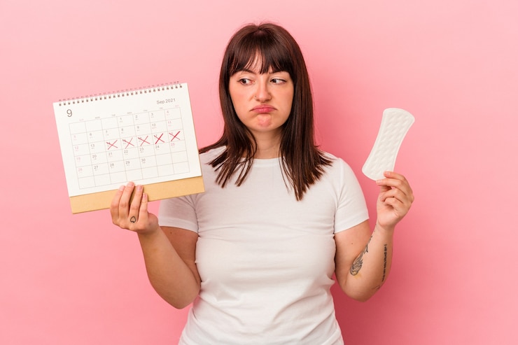Photo jeune femme de race blanche sinueuse tenant une compresse de calendrier isolée sur fond rose