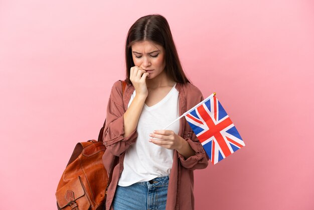 Jeune femme de race blanche tenant un drapeau du Royaume-Uni isolé ayant des doutes