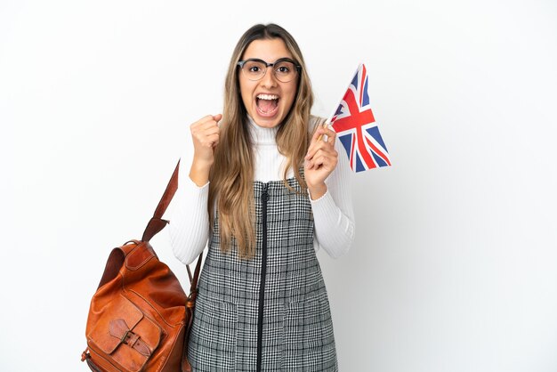 Jeune Femme De Race Blanche Tenant Un Drapeau Du Royaume-uni Isolé Sur Fond Blanc Célébrant Une Victoire En Position De Vainqueur