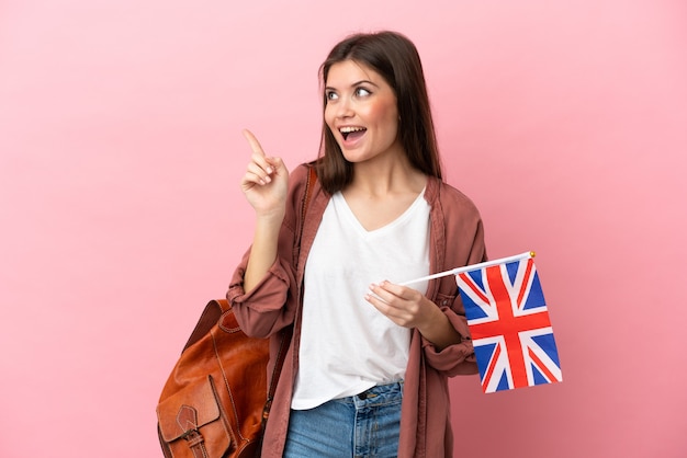 Jeune femme de race blanche tenant un drapeau du Royaume-Uni isolé sur fond rose dans l'intention de réaliser la solution tout en levant un doigt vers le haut