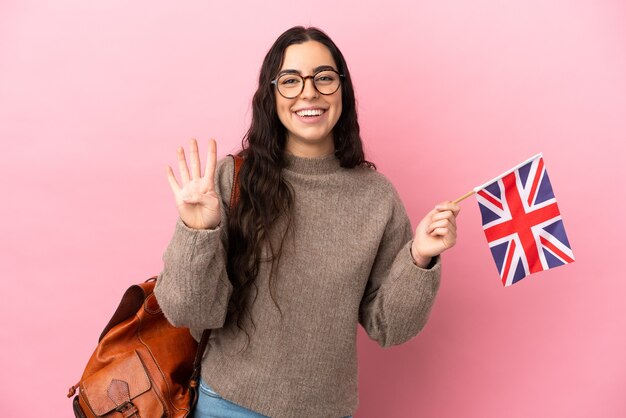 Jeune femme de race blanche tenant un drapeau du Royaume-Uni isolé sur fond rose heureux et en comptant quatre avec les doigts