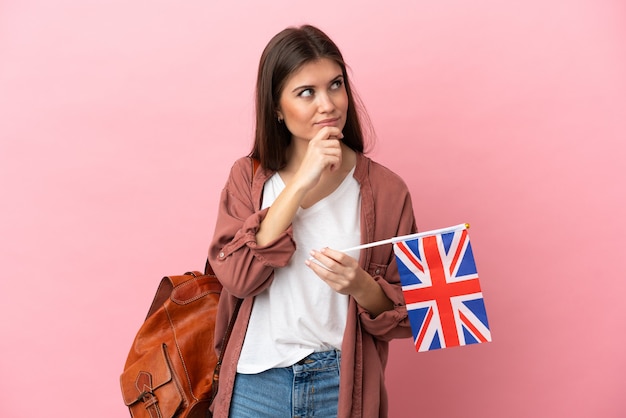 Jeune femme de race blanche tenant un drapeau du Royaume-Uni isolé et levant