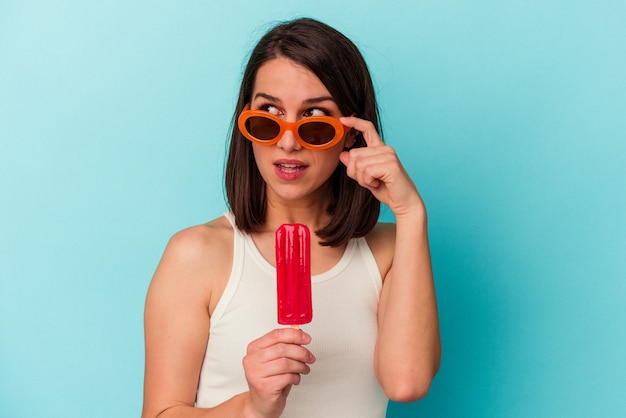 Jeune femme de race blanche tenant une glace isolée sur fond bleu