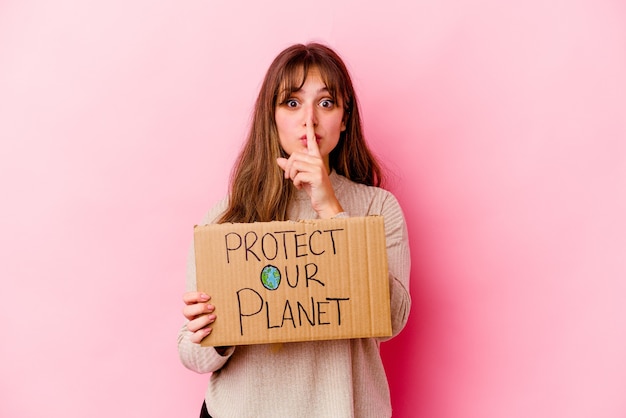 Jeune femme de race blanche tenant une pancarte Protégeons notre planète isolée en gardant un secret ou en demandant le silence.