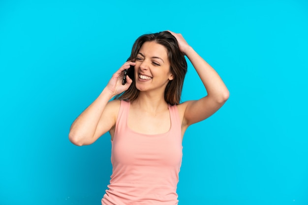 Jeune femme de race blanche utilisant un téléphone portable isolé sur fond bleu souriant beaucoup