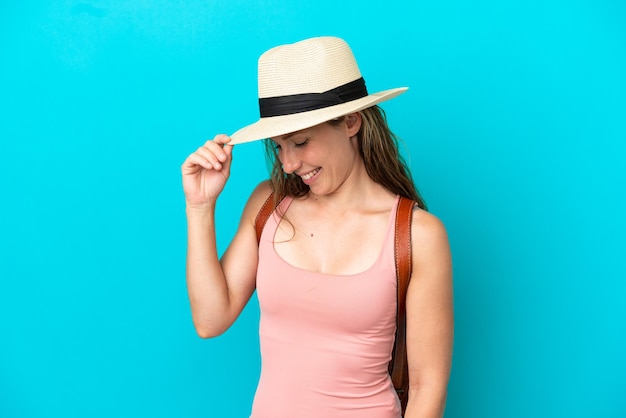 Jeune femme de race blanche en vacances d'été isolé sur fond bleu en riant